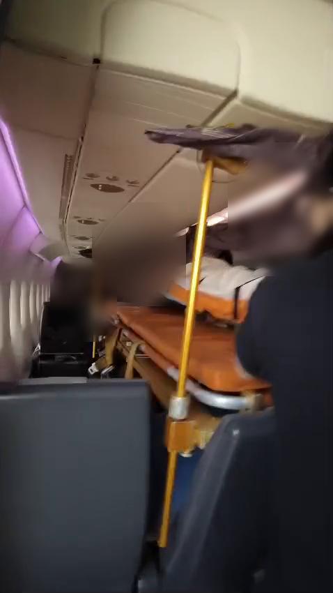 Commercial stretcher installation inside aircraft cabin (faces blurred)
