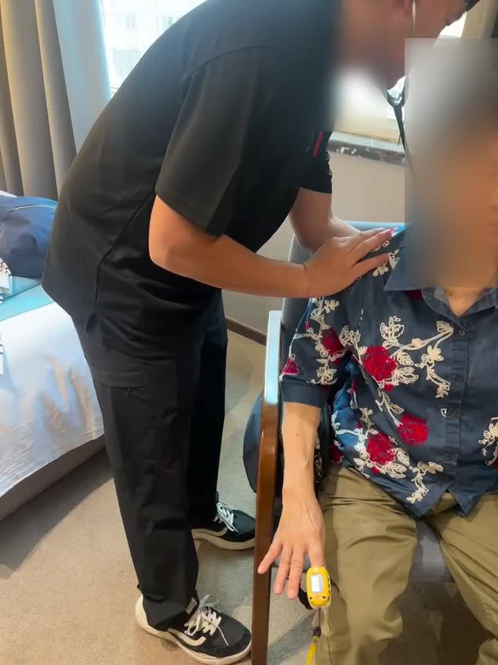 EMA medical escort assessing a patient during a commercial seated transfer (patient face blurred for privacy)