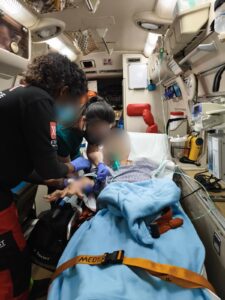 Medical team providing care inside a ground ambulance during transfer (faces blurred for privacy)