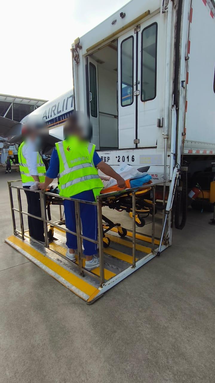 Stretcher boarding via China Eastern ambulift high-loader (faces blurred)